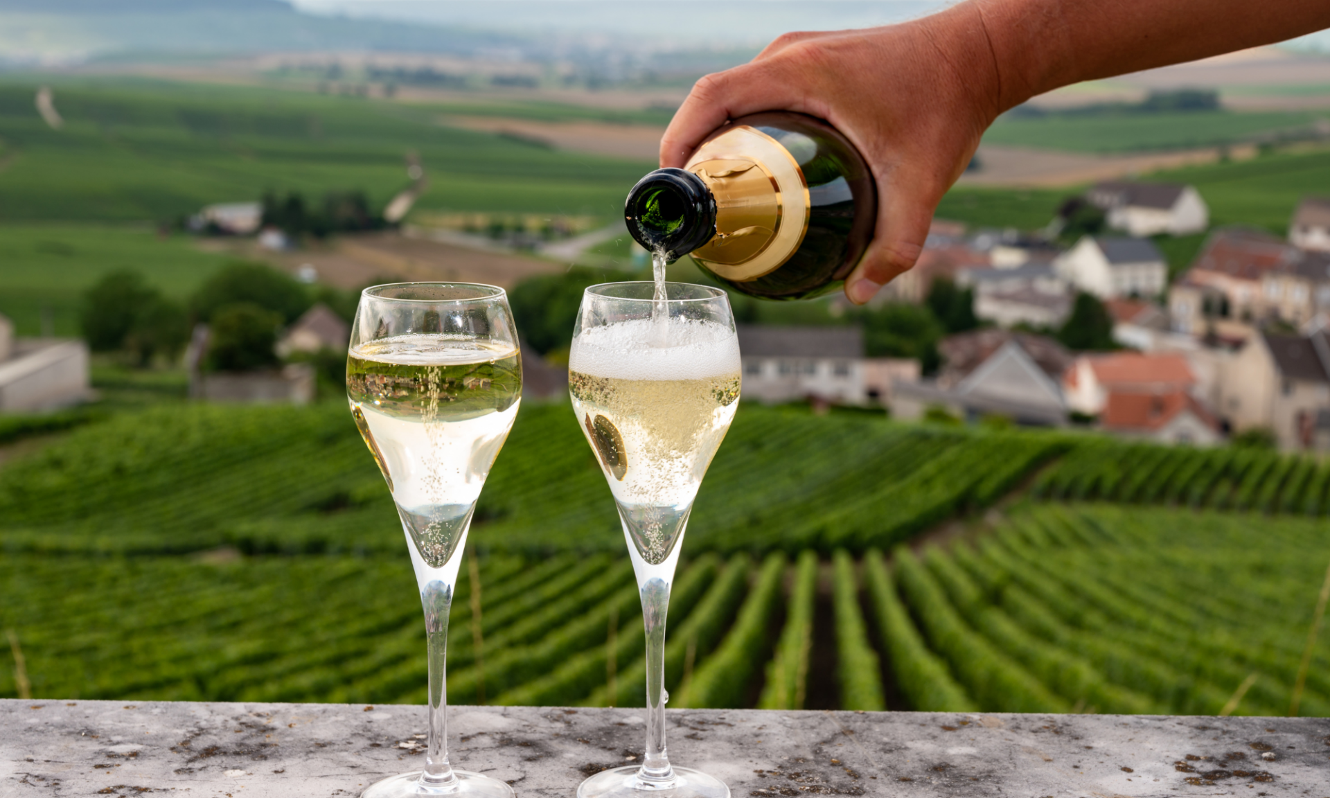 Pouring two glasses of champagne at an in-person wine tasting